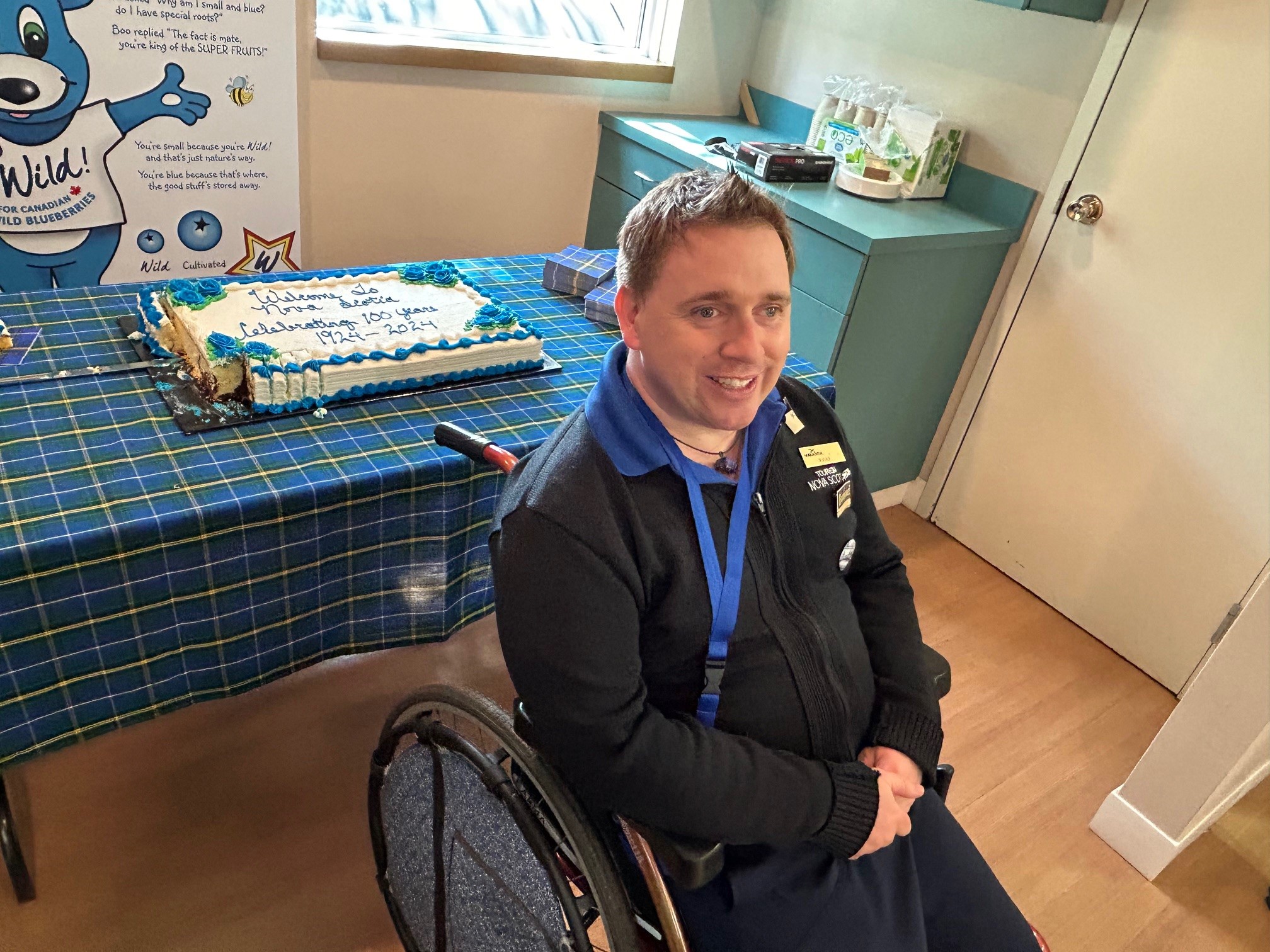 Man sitting in a wheel chair in front of a table with a cake on it