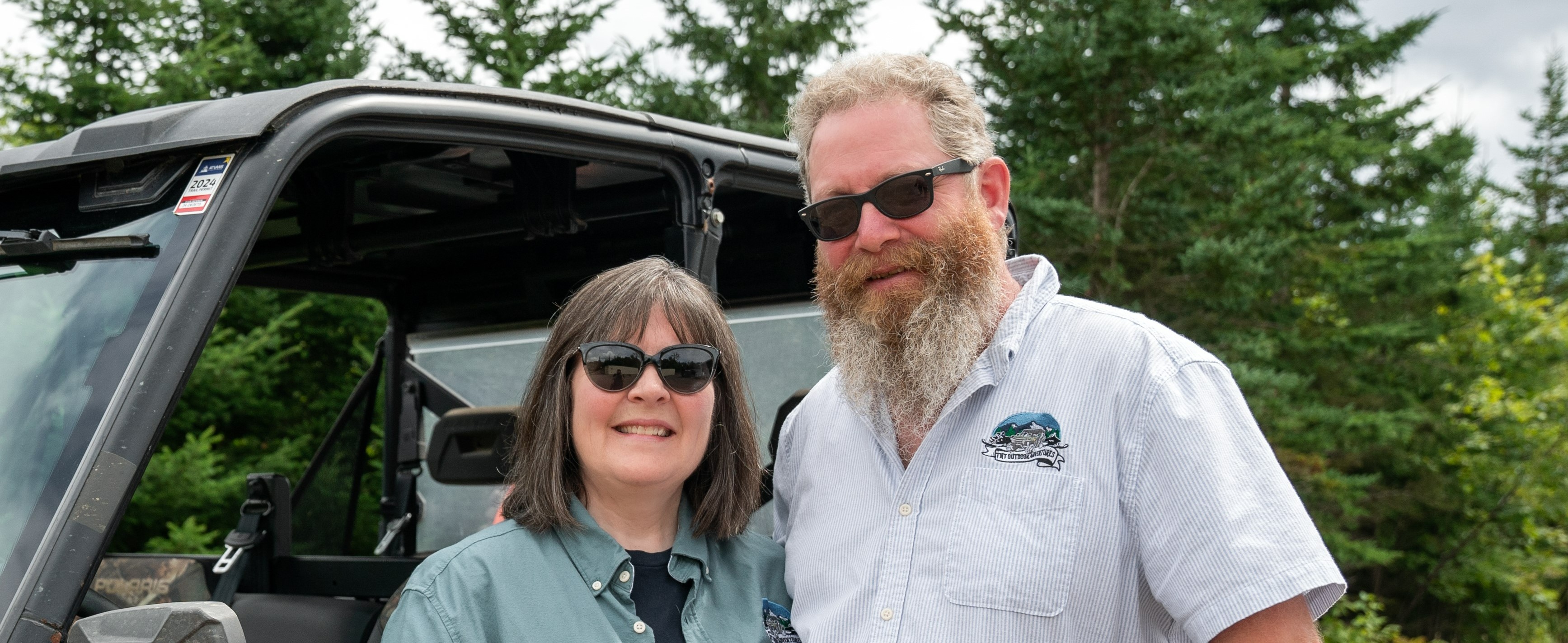 Two people standing in front of an off-road vehicle 