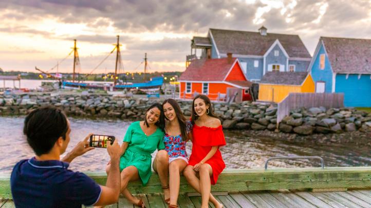 Man taking a photo of three women in front of the Ship Hector.