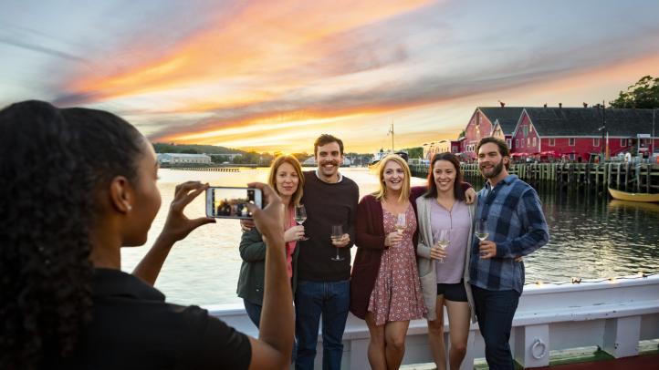 Woman taking a photo of a group of people on the wharf in Lunenburg.