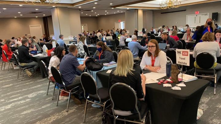 Large room with people sitting across from each other at the TMAC Media Marketplace