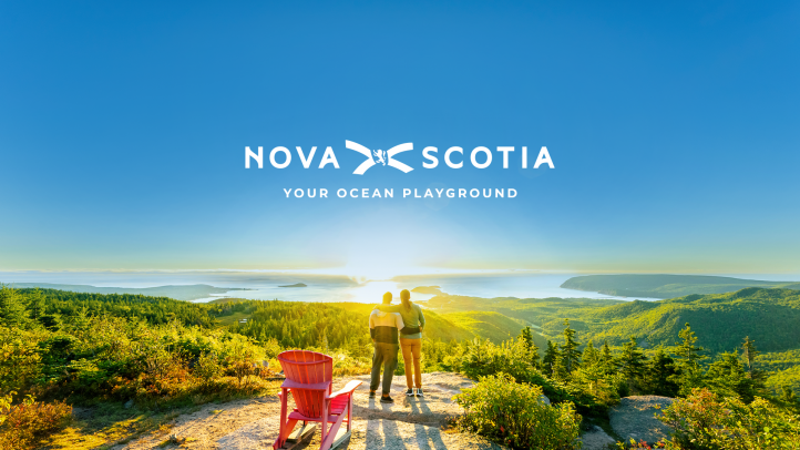 Two people at the top of Franey Trail in Cape Breton Highlands National Park. Text reads Nova Scotia Your Ocean Playground.