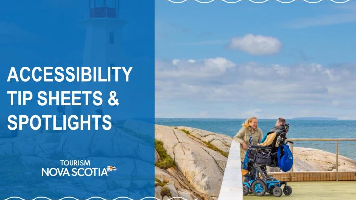 Two people, one in a wheelchair, on the deck of in front of a lighthouse beside the ocean.