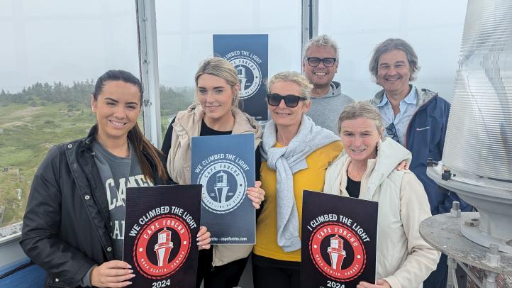 A group of visiting UK tour operators are pictured with their certificates for "Climbing the Light" at Cape Forchu.  