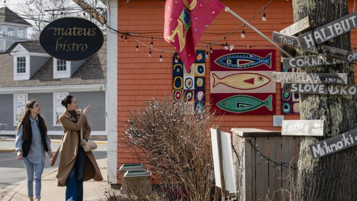 Two people walking along the sidewalk outside Mateus Bistro in Mahone Bay