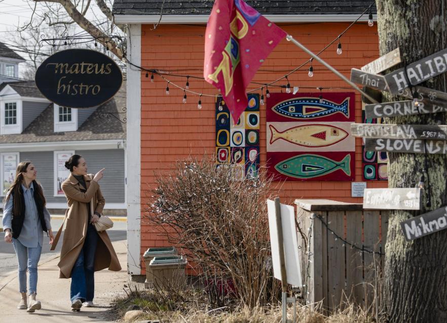 Two people walking along the sidewalk outside Mateus Bistro in Mahone Bay